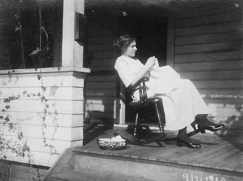 A photo of a woman sitting on a porch in a rocking chair. At the bottom, the date "9/7/1813" is written.